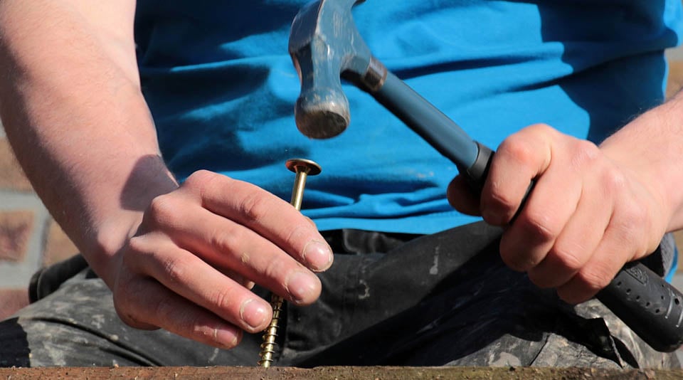 Handyman hammering a screw